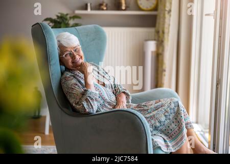Elderly woman sitting in an armchair in her home Stock Photo