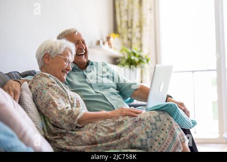 Happy senior couple using laptop at home Stock Photo