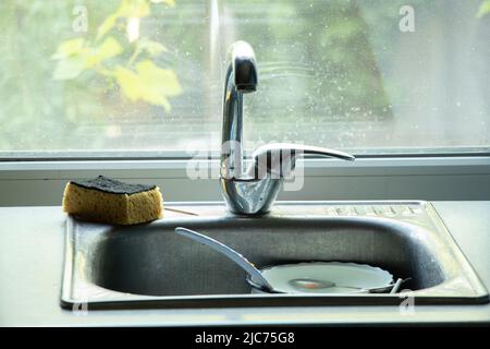 dirty dishes in the sink on the table in the kitchen under the tap, dirty dishes in mocha in the kitchen at home Stock Photo