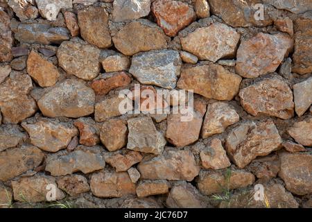 Old rough stone wall background. Village house stone wall. Front view. Stock Photo