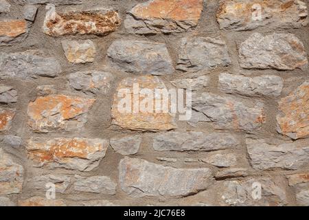 Stonewall is made of light orange and grey coloured stones. Front view and close up. Stock Photo