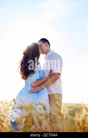 Stylish and modern couple kissing in a wheat field. A young woman hugs her boyfriend and kisses each other. The concept of passion and love. Selective Stock Photo