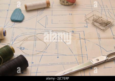 Image with a pattern, needles, thread and scissors for cutting fabric for making clothes following the pattern printed on paper. Copy space in the cen Stock Photo
