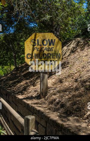 A warning sign 'Slow please children at  play that is weathered from the amount of time it has been in use in Santa Barbara County, California. Stock Photo