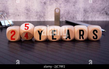 Hand turns dice and changes the expression 24 years to 25 years. Stock Photo