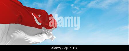 official flag of Islamic State  Indonesia at cloudy sky background on sunset, panoramic view. Indonesian travel and patriot concept. copy space for wi Stock Photo