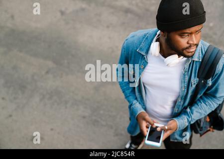 Black man with headphones using mobile phone while standing outdoors Stock Photo
