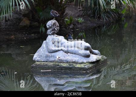 Beautiful birds on a woman sculpture on a lake in the park. Stock Photo