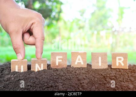 Justice and fairness concept. Hand changing unfair to fair word on wooden blocks. Stock Photo