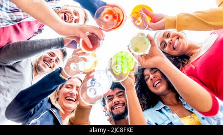 directly below portrait of interracial group of friends holding gourmet cocktails outdoors laughing and having fun. diverse people celebrating life t Stock Photo