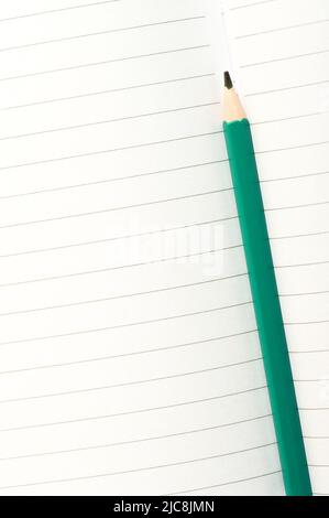 Aqua blue pencil on an open notebook. Close up image of a pencil on white paper. Stock Photo