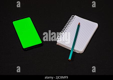 Composition, notebook with a mobile with a green screen. Stock Photo