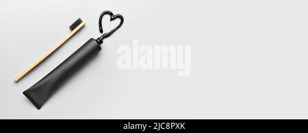 Tube with activated charcoal toothpaste and bamboo brush on light background with space for text Stock Photo
