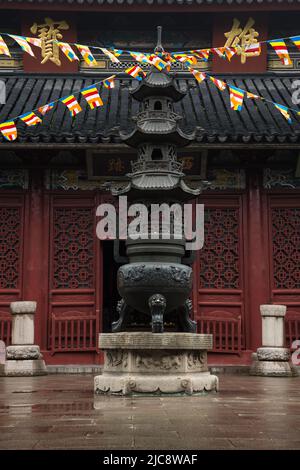 A large bronze incense burner and prayer flags in front of the Grand Prcious Hall, West Garden Temple in Suzhou, China. Stock Photo