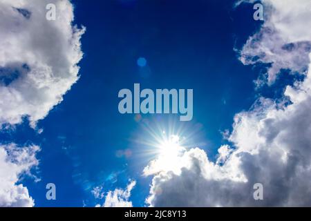 a heavenly landscape with a bright sun breaking through the clouds in a blue sky Stock Photo