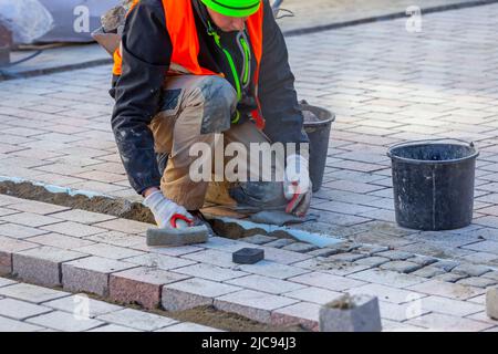 A worker lays paving stones on the sidewalk. Gdansk Stock Photo