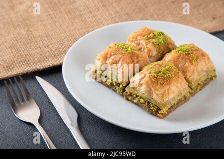 Traditional pistachio baklava in white plate.A plate baklava on dark background Stock Photo