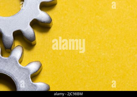 two gears geared on a yellow background with copy space, geared steel sprockets, sprocket, background with gearing parts, horizontal Stock Photo