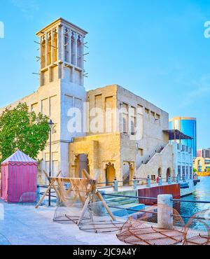 The vintage adobe house with windcather (barjeel) tower on the bank of Dubai Creek with a view on traditional fishing traps and nets in the foreground Stock Photo