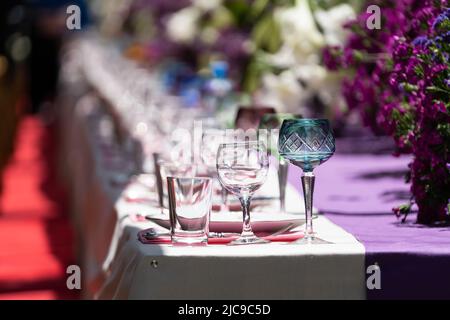 Decoration festival table with purple and white flowers and glassware on tablecloth. Selective focus Stock Photo