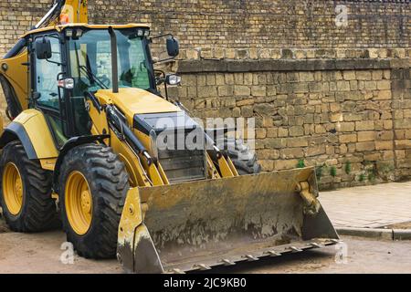 wheeled bucket loader next to a brick wall Stock Photo