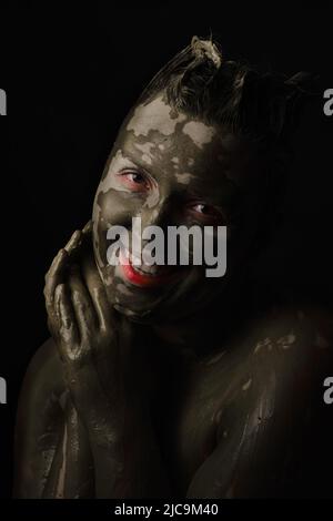 fun woman with black dirty smeared make up on black background Stock Photo