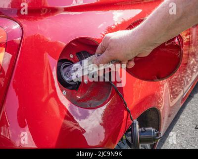 Petrol diesel fuel price rise crisis filling up the auto car vehicle at a gas service station in 2022 cash illustration in tank Stock Photo