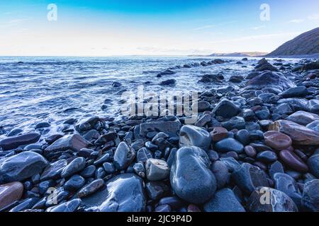 Colourful Wet Rocks on Bucks Mills Beach at High Tide with View of the Beach and North Devon Coastline,  Bucks Mills, Devon, Great Britain. Stock Photo