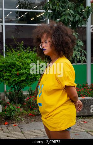 Medellin, Antioquia, Colombia - February 19 2022: Brunette Woman with Curly Hair very Similar to Singer Rihanna, Wears a Yellow Shirt and Glasses Stock Photo