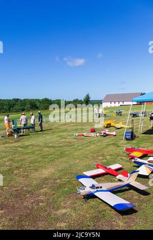BETHLEHEM, NC, USA-28 MAY 2022: Multiple RC (radio-controlled) model planes set, waiting to be flown.  Owners in background. Stock Photo