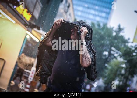 Ankara, Turkey. 11th June, 2022. A man shelters from rain beneath a coat. Heavy rains fall in Ankara, the capital of Turkey. (Photo by Tunahan Turhan/SOPA Images/Sipa USA) Credit: Sipa USA/Alamy Live News Stock Photo