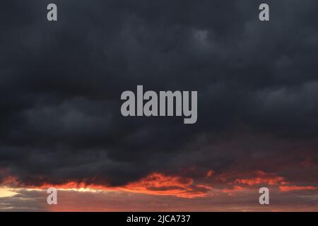 Thunderclouds with breaking rays sun at sunset Stock Photo