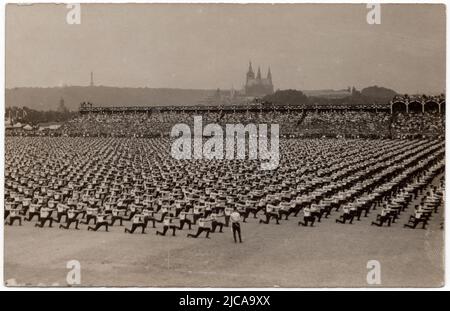 Sokol athletes perform during the 5th Sokol mass gymnastics festival (V. všesokolský slet) in July 1907 on the Letná Plateau (Letenská pláň) in Prague, Austria-Hungary. Black and white vintage photograph by an unknown photographer published on the vintage postcard issued in occasion of the 5th Sokol mass gymnastics festival. Saint Vitus' Cathedral in Prague Castle is seen in the background. Courtesy of the Azoor Postcard Collection. Stock Photo