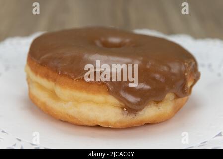 Tempting fresh from the oven maple donut from the bakery served on a plate. Stock Photo