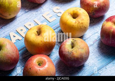 Many yellow and red apples fruit with apples word written on wooden letters on a blue background Stock Photo