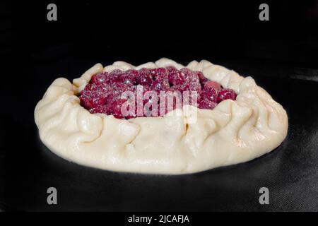 Uncooked homemade galette, open pie with cherry baking in electric oven Stock Photo