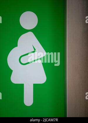 Symbol of a Pregnant Woman on a Green Door Stock Photo