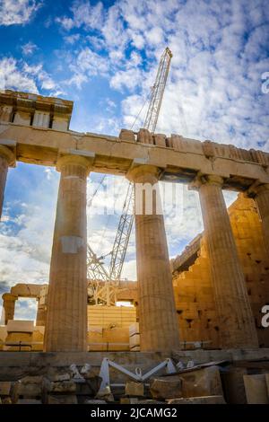 Parthenon on Acropolis in Athens under construction with tall crane under beautiful sky with sun shinning through Stock Photo