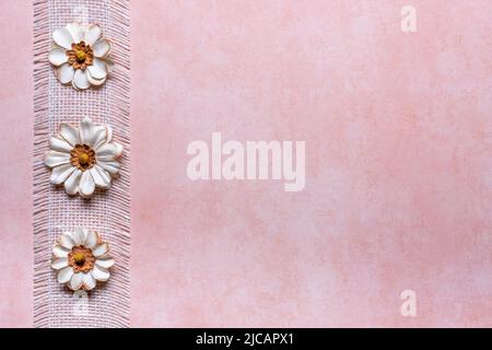 peach textured background with white burlap ribbon and 3 flower left border Stock Photo