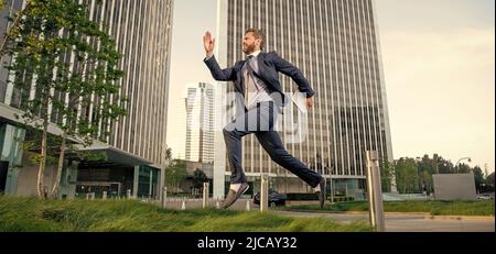 successful man in formalwear jumping with computer outside the office, technology Stock Photo