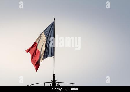 Picture of a French flag waving in the air. The national flag of France, or drapeau francais is a tricolour flag featuring three vertical bands colour Stock Photo