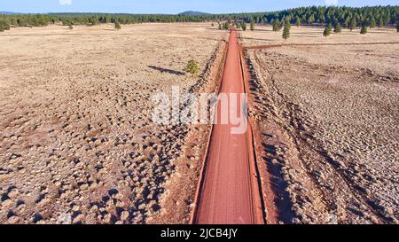 Red dirt road straight through desert plains from aerial view Stock Photo