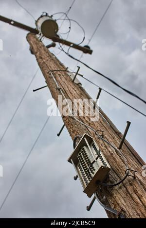 Telephone pole looking up detail on cloudy day for communication and power Stock Photo