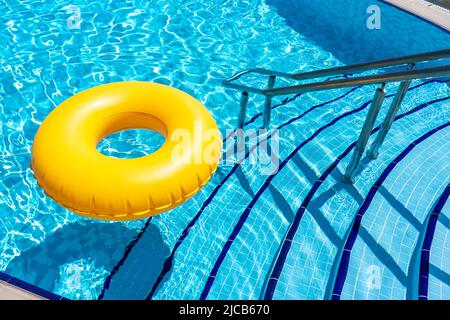 Yellow inflatable ring floating in swimming pool. Vacation concept with copy space Stock Photo