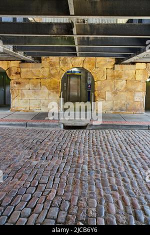 Red brick road under bridge leading to modern elevator Stock Photo