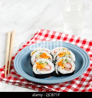 Gimbap or Kimbap, Korean Roll Rice with Nori Laver, Sesame Seed, and Various Vegetable. Served on Blue Plate Stock Photo