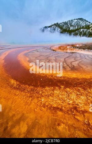 Red and orange spiral in spring of Yellowstone by winter mountains Stock Photo
