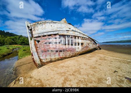 Side hull of red and white shipwreck on sandy beaches with blue sky Stock Photo