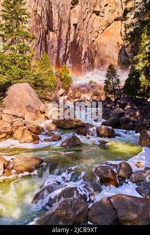 Rainbow over frosty aqua river in early spring at Yosemite Stock Photo