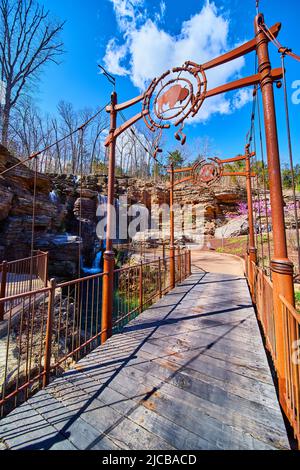 Looking down short and artsy walking bridge in early spring leading to waterfalls Stock Photo